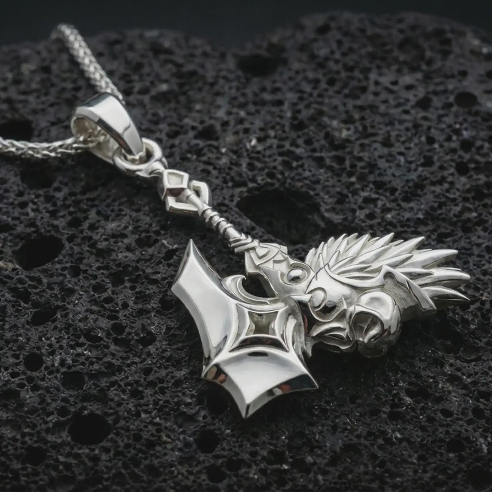 Polished silver paladin hammer pendant necklace displayed on black volcanic rock, shown in a refined macro product shot with medieval weapon detail, spiked head, and knightly ornamentation.