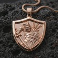 Load image into Gallery viewer, Rose gold plated samurai shield pendant necklace on dark volcanic rock, photographed in a detailed premium studio macro view.
