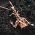 Load image into Gallery viewer, Rose gold plated Baphomet pendant necklace on dark volcanic rock, photographed in a detailed premium studio macro view.
