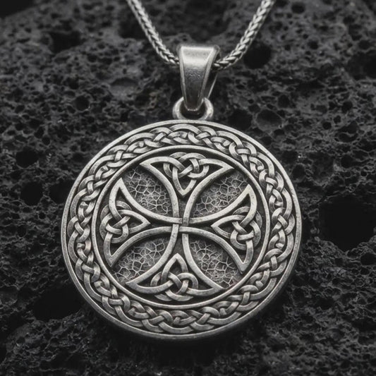 Sterling silver Celtic knot medallion necklace with an oxidized finish resting on textured volcanic rock, captured in a close-up premium studio composition.