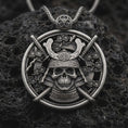 Load image into Gallery viewer, Sterling silver samurai skull pendant necklace with an oxidized finish resting on textured volcanic rock, captured in a close-up premium studio composition.
