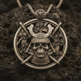 Load image into Gallery viewer, Bronze samurai skull pendant necklace with an oxidized finish resting on textured volcanic rock, captured in a close-up premium studio composition.
