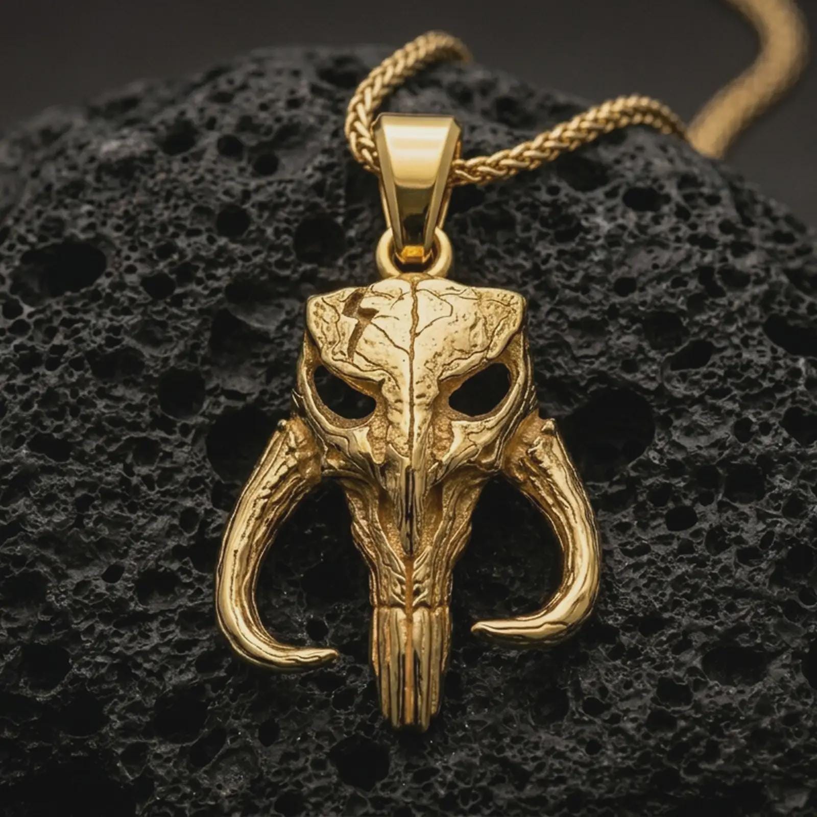 Gold plated Mythosaur skull pendant necklace presented on porous volcanic rock, highlighting the iconic warrior emblem in a luxurious close-up jewelry image.