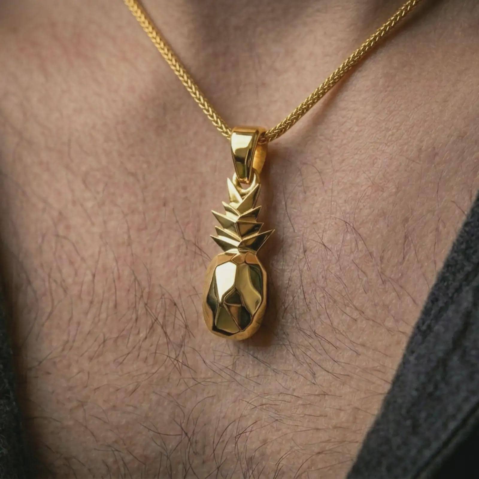 Gold plated origami pineapple pendant necklace worn on the neck, captured on a human model in a premium dark-toned lifestyle frame.