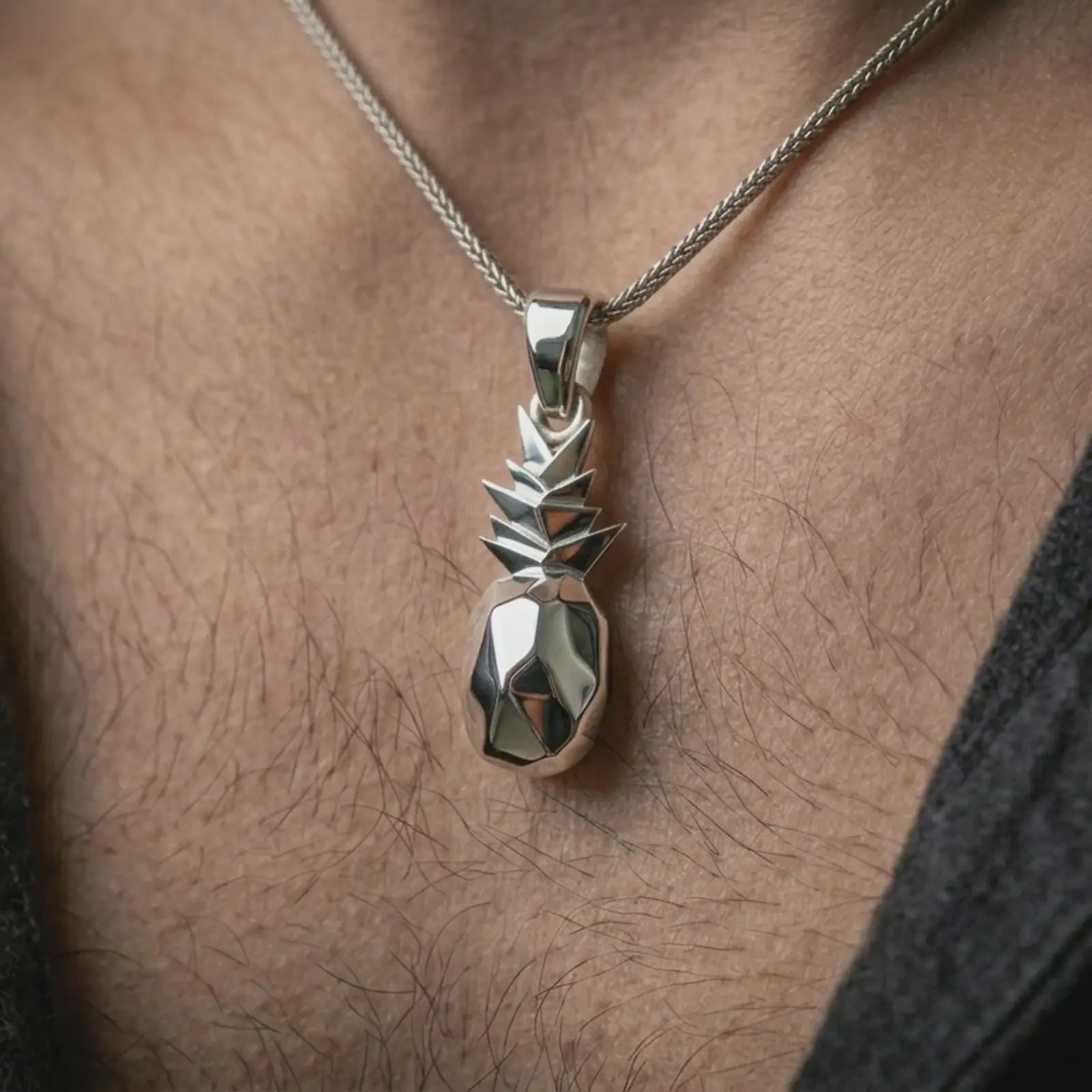 Polished silver origami pineapple pendant necklace worn on the neck, shown against the chest in a clean and elegant everyday wear composition.