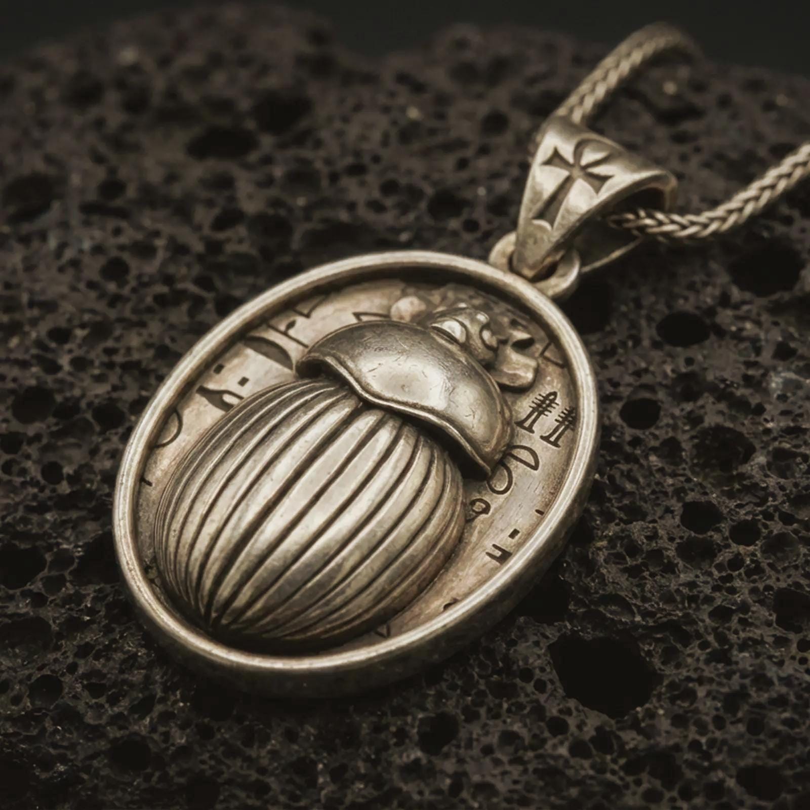 Bronze Egyptian scarab pendant necklace with an oxidized finish resting on textured volcanic rock, captured in a close-up premium studio composition.