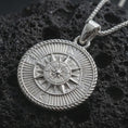 Load image into Gallery viewer, Polished silver steampunk compass pendant necklace displayed on black volcanic rock, shown in a refined macro product shot with detailed directional markers, layered compass rose, and vintage explorer styling.
