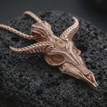 Load image into Gallery viewer, Rose gold plated Baphomet skull pendant necklace on dark volcanic rock, photographed in a detailed premium studio macro view.
