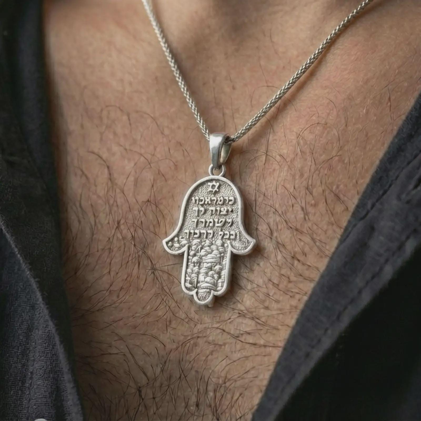Polished silver Jerusalem Hamsa hand pendant necklace worn on the neck, shown against the chest in a clean and symbolic everyday wear composition.