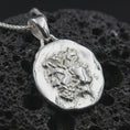 Load image into Gallery viewer, Polished silver Janus coin pendant necklace displayed on dark volcanic rock, shown in a premium macro product shot that highlights the dual face motif and worn classical medallion texture.
