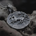 Load image into Gallery viewer, Oxidized Janus coin pendant necklace resting on black volcanic stone, featuring the ancient Roman two-faced god in a detailed antique-style relief and organic coin-shaped silhouette.
