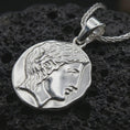 Load image into Gallery viewer, Polished silver ancient Greek coin pendant necklace displayed on dark volcanic rock, shown in a premium macro product shot that highlights the feminine side profile and sculpted coin edge.
