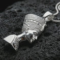 Load image into Gallery viewer, Polished silver Nefertiti pendant necklace displayed on black volcanic rock, shown in a refined macro product shot with regal Egyptian queen profile, detailed crown, and sculptural bust relief.
