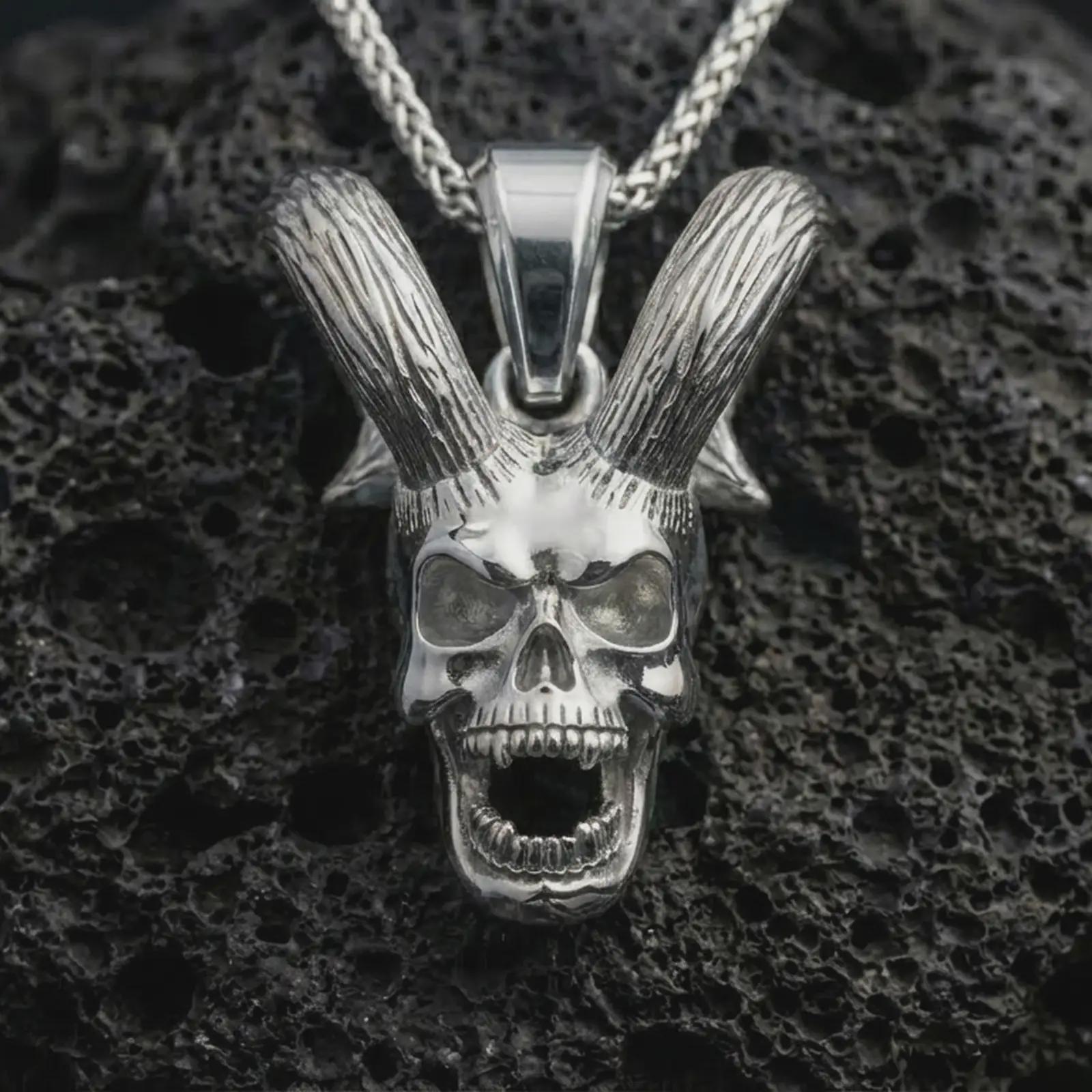Polished silver rabbit skull pendant necklace displayed on black volcanic rock, shown in a refined macro product shot with long upright ears, open jaw, and gothic skull detail.