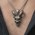 Load image into Gallery viewer, Oxidized rabbit skull pendant necklace worn on the neck, styled in a dark lifestyle portrait with an open shirt and bold presentation.
