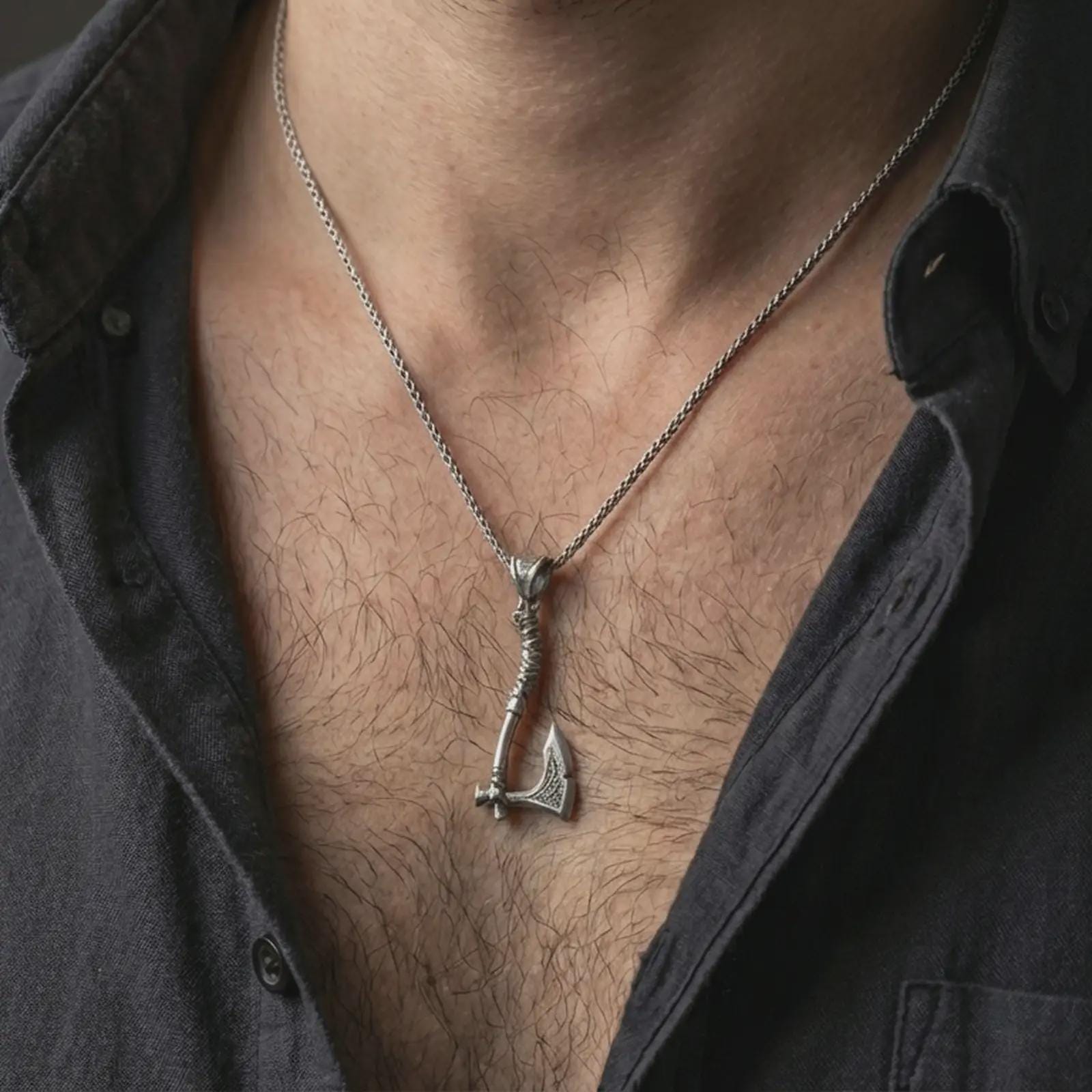 Oxidized battle axe pendant necklace worn on the neck, styled in a dark lifestyle portrait with an open shirt and bold masculine presentation.