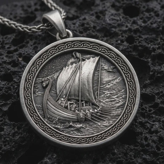 Sterling silver Viking ship pendant necklace with an oxidized finish resting on textured volcanic rock, captured in a close-up premium studio composition.