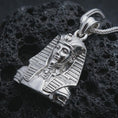 Load image into Gallery viewer, Polished silver Tutankhamun pendant necklace displayed on black volcanic rock, shown in a refined macro product shot with pharaoh headdress, sculptural facial detail, and ancient Egyptian royal styling.
