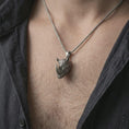 Load image into Gallery viewer, Oxidized rhinoceros head pendant necklace worn on the neck, styled in a dark lifestyle portrait with an open shirt and bold masculine presentation.
