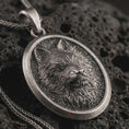 Load image into Gallery viewer, Sterling silver snarling wolf pendant necklace with an oxidized finish resting on textured volcanic rock, captured in a close-up premium studio composition.
