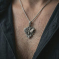 Load image into Gallery viewer, Oxidized floral bee pendant necklace worn on the neck, styled in a dark lifestyle portrait with an open shirt and elegant nature-inspired presentation.
