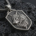 Load image into Gallery viewer, Sterling silver wolf shield pendant necklace with an oxidized finish resting on textured volcanic rock, captured in a close-up premium studio composition.

