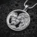 Load image into Gallery viewer, Polished silver lion and bear family pendant necklace displayed on black volcanic rock, shown in a refined macro product shot with intertwined adult animals, cub detail, and circular unity frame.
