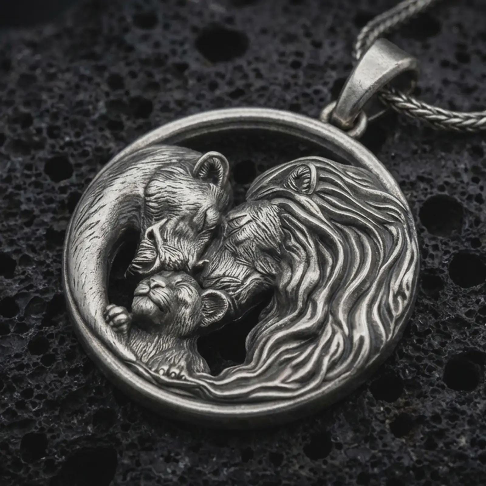 Sterling silver lion and bear family pendant necklace with an oxidized finish resting on textured volcanic rock, captured in a close-up premium studio composition.