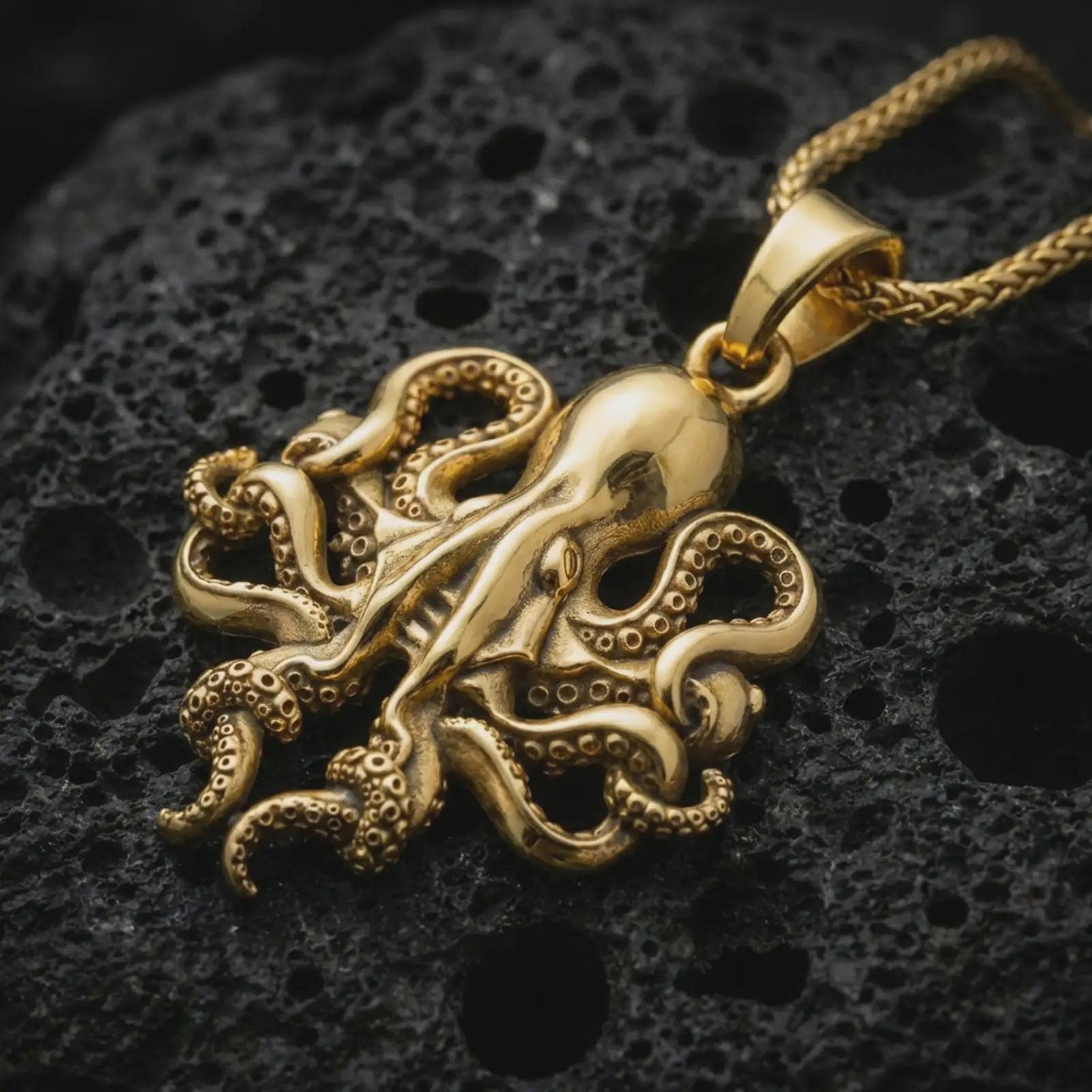 Gold plated octopus pendant necklace presented on porous volcanic rock, highlighting the sea creature silhouette in a luxurious close-up jewelry image.