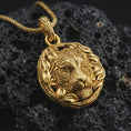 Load image into Gallery viewer, A gold plated tiger pendant on black volcanic stone with bright reflections across the tiger muzzle and leaf border.
