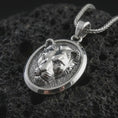 Load image into Gallery viewer, Polished silver lioness pendant necklace displayed on black volcanic rock, shown in a refined macro product shot with feline face relief, smooth oval medallion frame, and powerful wildlife detail.

