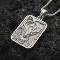 Load image into Gallery viewer, Polished silver stag forest pendant necklace displayed on black volcanic rock, shown in a refined macro product shot with majestic antlers, woodland branches, ivy leaves, and framed nature relief.

