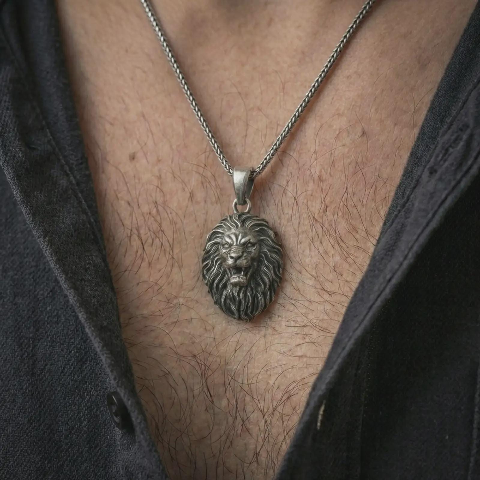 Oxidized roaring lion head pendant necklace worn on the neck, styled in a dark lifestyle portrait with an open shirt and bold masculine presentation.