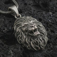 Load image into Gallery viewer, Sterling silver roaring lion head pendant necklace with an oxidized finish resting on textured volcanic rock, captured in a close-up premium studio composition.
