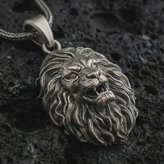 Sterling silver roaring lion head pendant necklace with an oxidized finish resting on textured volcanic rock, captured in a close-up premium studio composition.