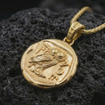 Load image into Gallery viewer, Gold plated Athena owl coin pendant necklace photographed on porous black volcanic stone, emphasizing the classical Greek owl design and historic medallion silhouette in a luxury jewelry composition.
