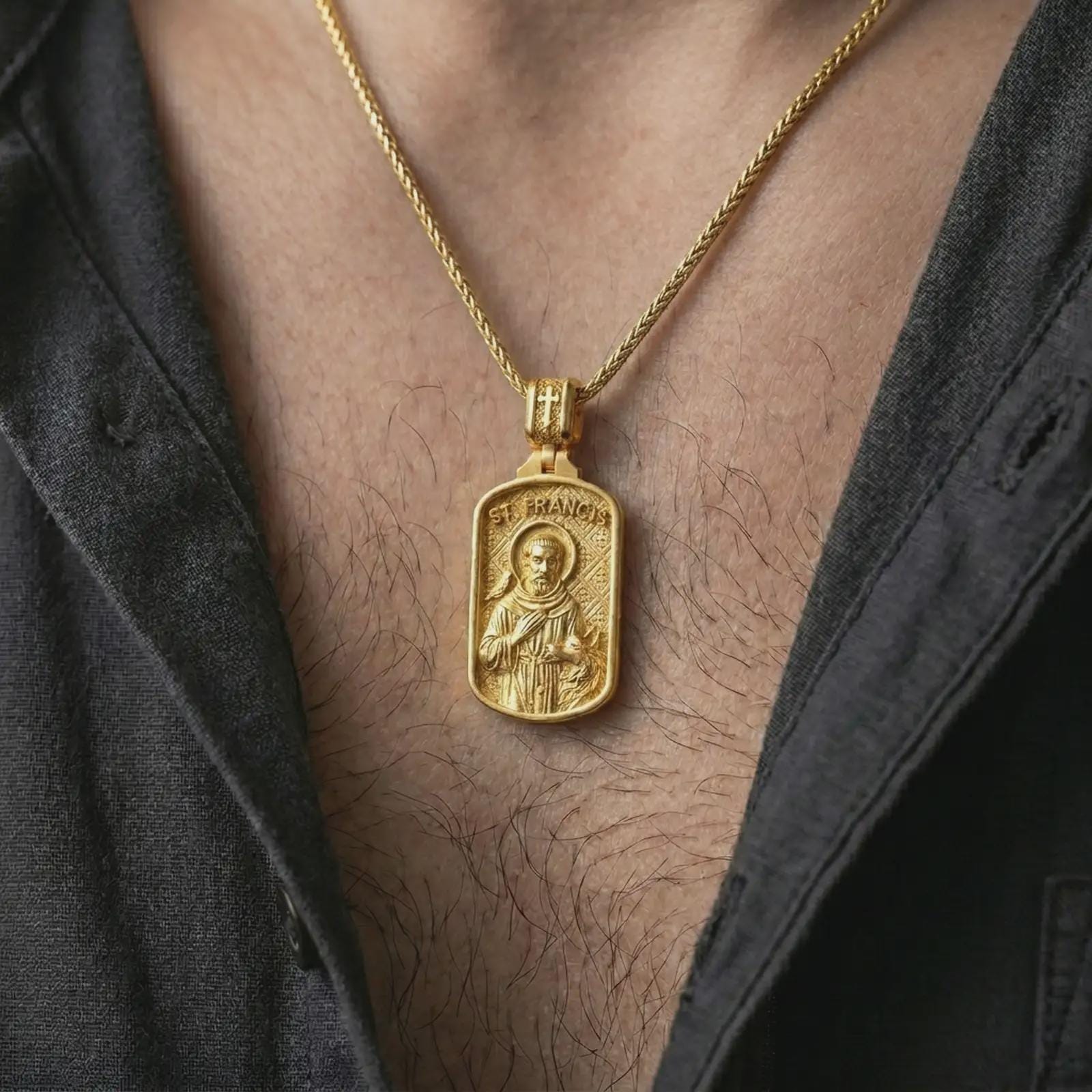 Gold plated Saint Francis pendant necklace worn on the chest, premium lifestyle jewelry photo with the Saint Francis medal centered on a spiga chain.