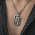 Load image into Gallery viewer, Oxidized Saint Joseph and Jesus pendant necklace worn on the chest, close-up lifestyle jewelry photo showing the religious medallion on a spiga chain with dark clothing.
