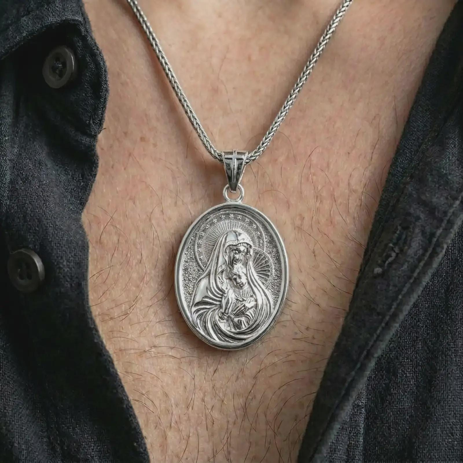 Polished silver Virgin Mary and baby Jesus pendant necklace worn on the chest, masculine lifestyle shot highlighting the Madonna and child relief, halo detail, and bright silver finish.