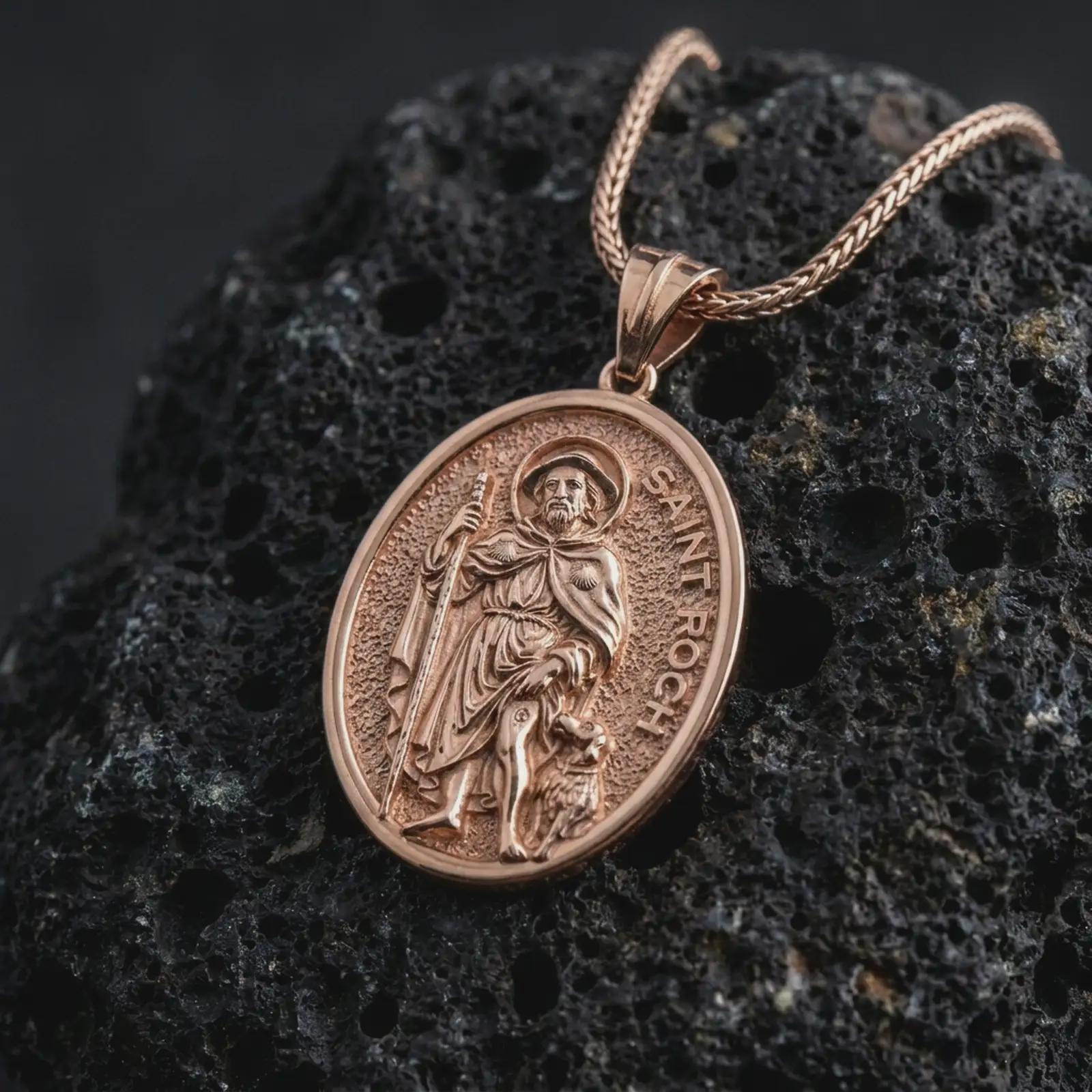 Rose gold plated Saint Roch pendant necklace on textured volcanic rock, detailed macro product shot with soft warm reflections and devotional healing saint design.