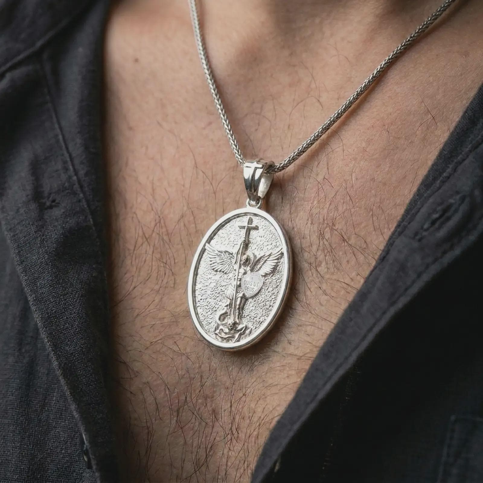 Polished silver Saint Michael pendant necklace worn on the chest, masculine lifestyle shot highlighting the sword, wings, shield detail, and bright silver finish.