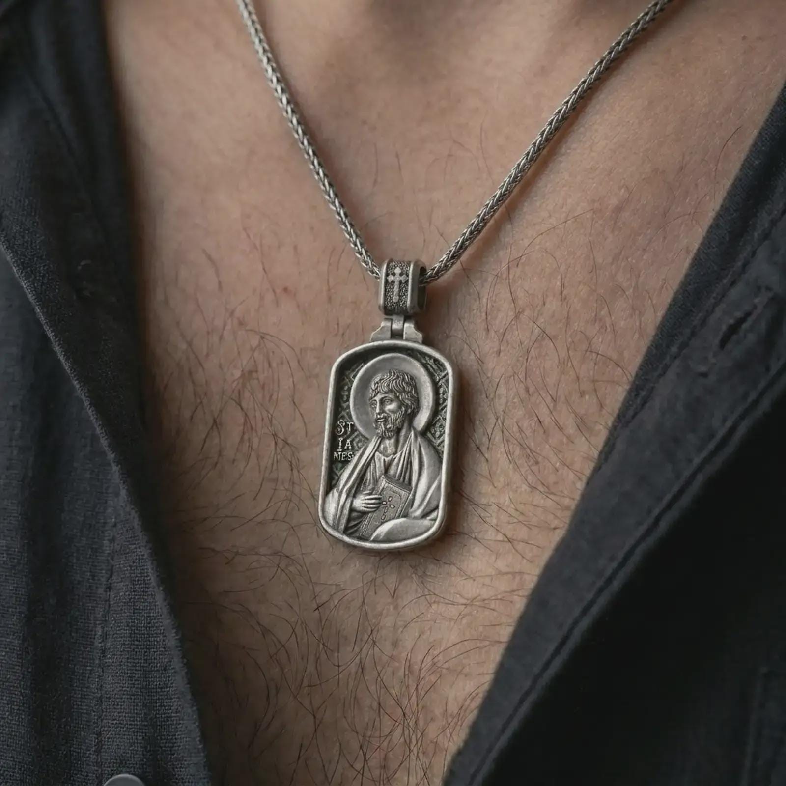 Oxidized Saint James the Apostle pendant necklace worn on the chest, close-up lifestyle jewelry photo showing the Catholic medallion on a spiga chain with dark clothing.