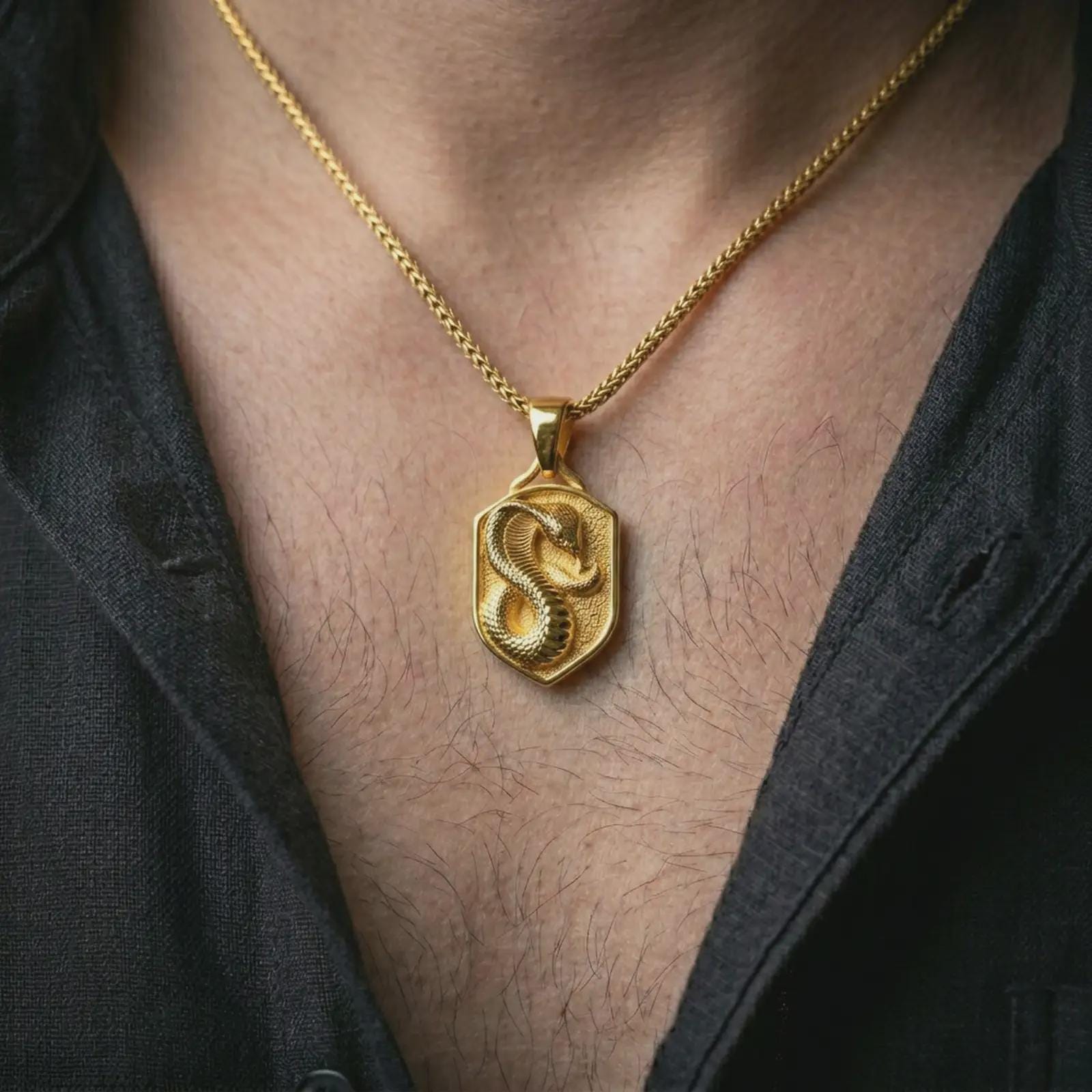 Gold plated cobra shield pendant necklace worn on the neck, captured on a human model in a premium dark-toned lifestyle frame.