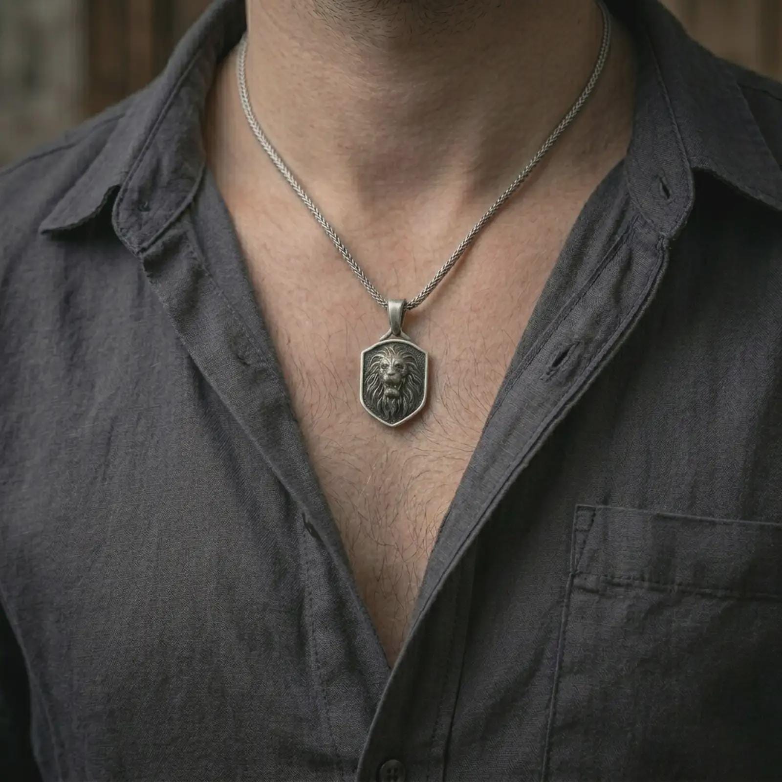 Oxidized roaring lion shield pendant necklace worn on the neck, styled in a dark lifestyle portrait with an open shirt and bold masculine presentation.