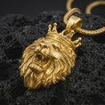 Load image into Gallery viewer, Gold plated crowned lion head pendant necklace presented on porous volcanic rock, highlighting the regal predator motif in a luxurious close-up jewelry image.
