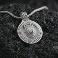 Load image into Gallery viewer, Polished silver Fenrir wolf pendant necklace displayed on black volcanic rock, shown in a refined macro product shot with detailed wolf head relief, circular sunburst border, and Norse-inspired medallion design.
