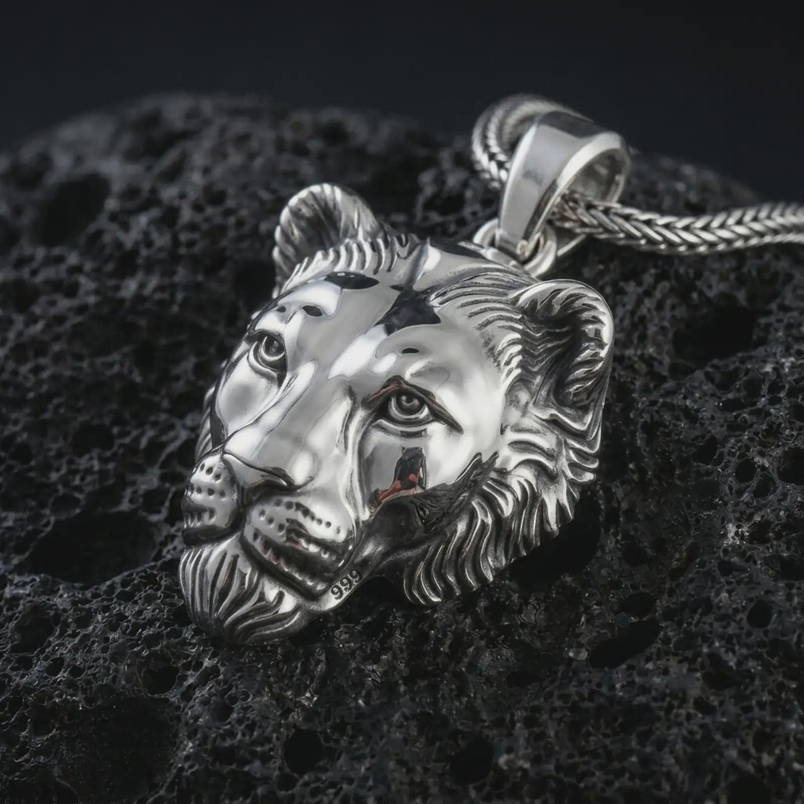 Polished silver 3D lioness pendant necklace displayed on black volcanic rock, shown in a refined macro product shot with realistic feline face sculpting, soft mane detail, and powerful safari-inspired presence.