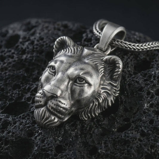 Sterling silver 3D lioness pendant necklace with an oxidized finish resting on textured volcanic rock, captured in a close-up premium studio composition.