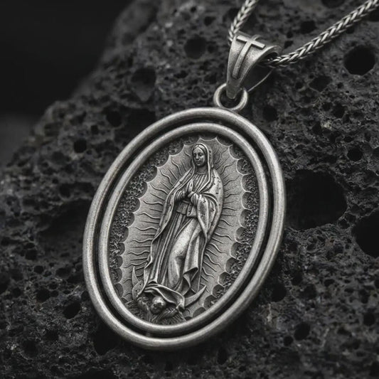 Oxidized Our Lady of Guadalupe spinner pendant necklace on textured volcanic rock, close-up studio shot highlighting the Virgin Mary relief, radiant halo, crescent moon, and antique silver contrast.