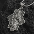 Load image into Gallery viewer, Oxidized Good Shepherd cross pendant necklace on textured volcanic rock, close-up studio shot highlighting the Jesus relief, lamb, shepherd staff, ornate cross frame, and antique silver contrast.
